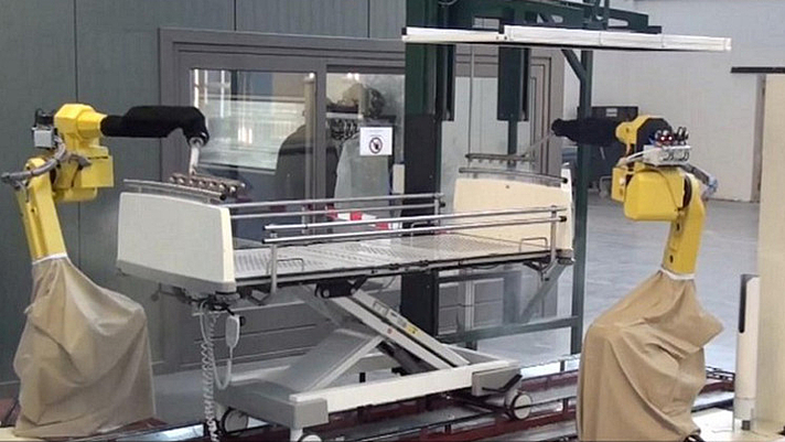 Photo: zwei Roboterarme reinigen ein Bettgestell 
