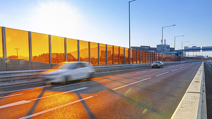 Photo: Schräger Blick auf Autobahn mit Lärmschutzwand im Sonnenlicht