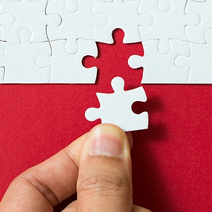 Photo: Hand fügt letztes Puzzelstück ein