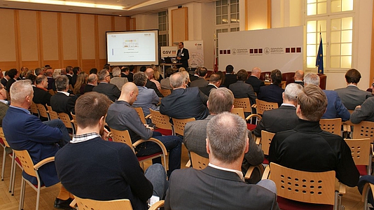 Photo: Teilnehmer der Veranstaltung im Publikum hören eine Präsentation 