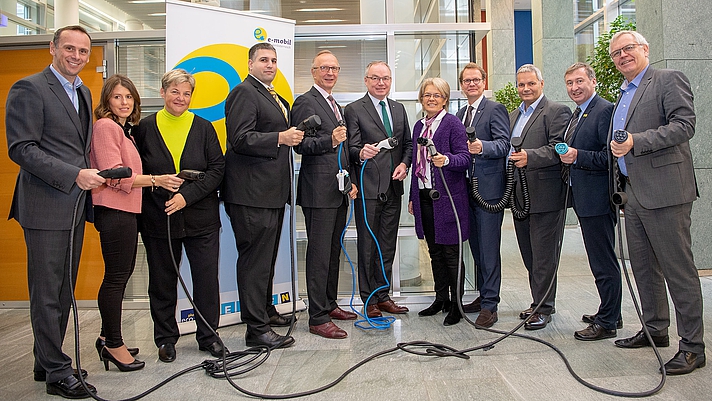 Photo: Teilnehmer der Pressekonferenz posieren mit Ladekabeln 