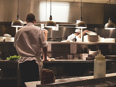 Photo: Blick in eine Großküche, in der zwei Personen kochen