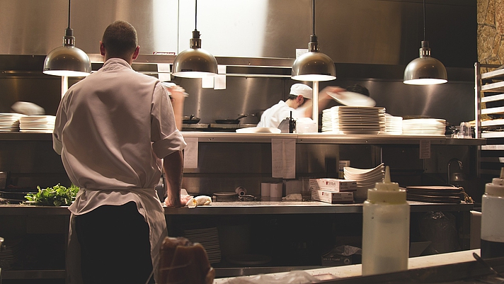 Photo: Blick in eine Großküche, in der zwei Personen kochen
